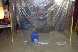 Plastic containment set up around basement plumbing work